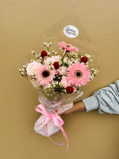 Bouquet with pink gerberas, pink roses, white wax flowers, and red gomphrena.