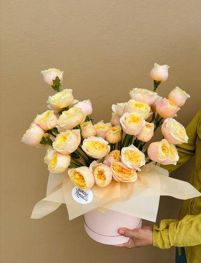 A hatbox arrangement of creamy peach and golden yellow roses.